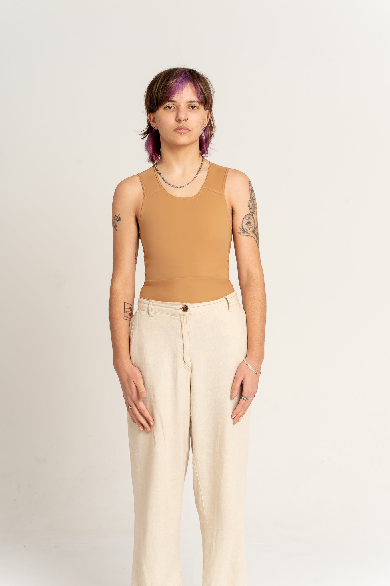 Person wearing a 'medium' coloured long chest binder and beige trousers against a plain background