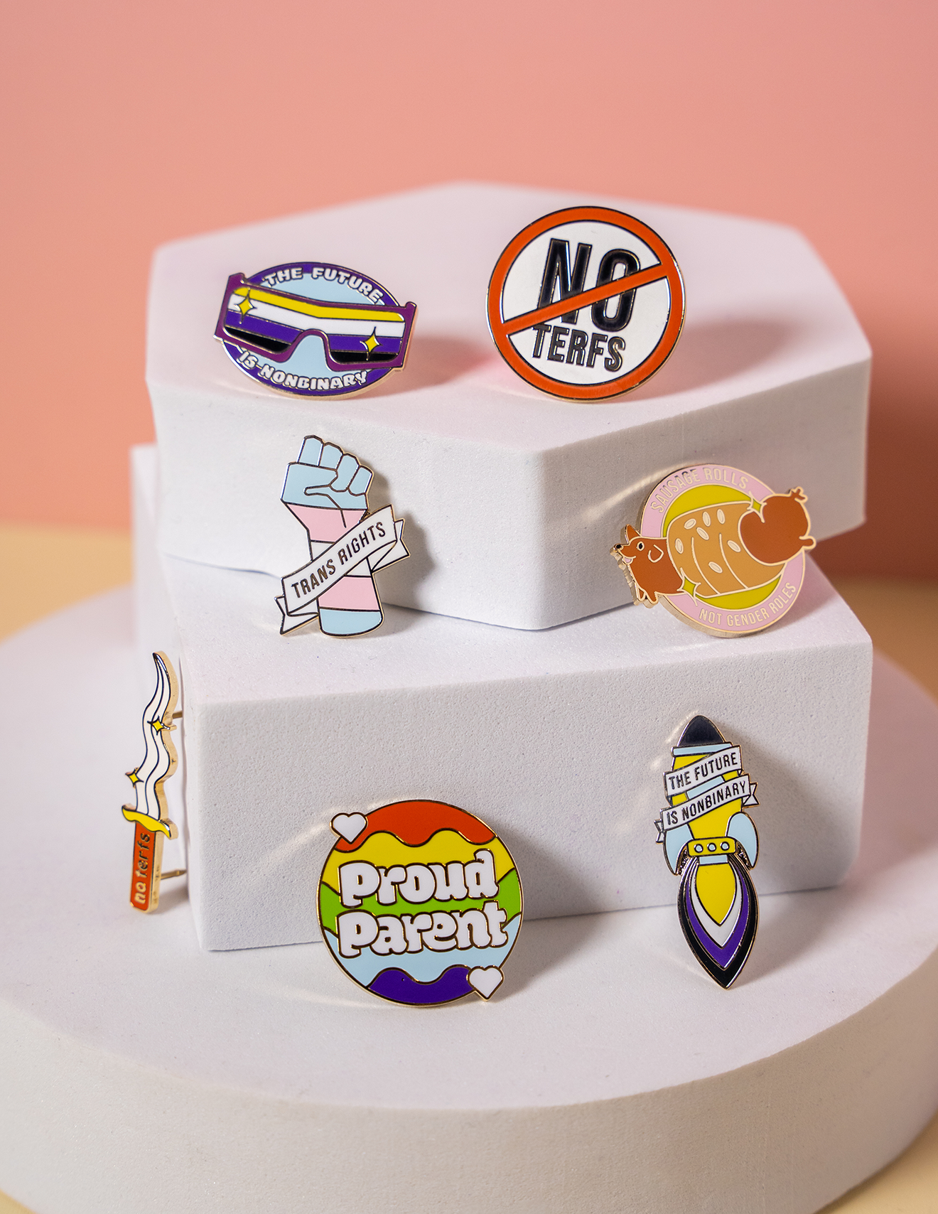 Collection of colorful queer pins on a white box with a pink background