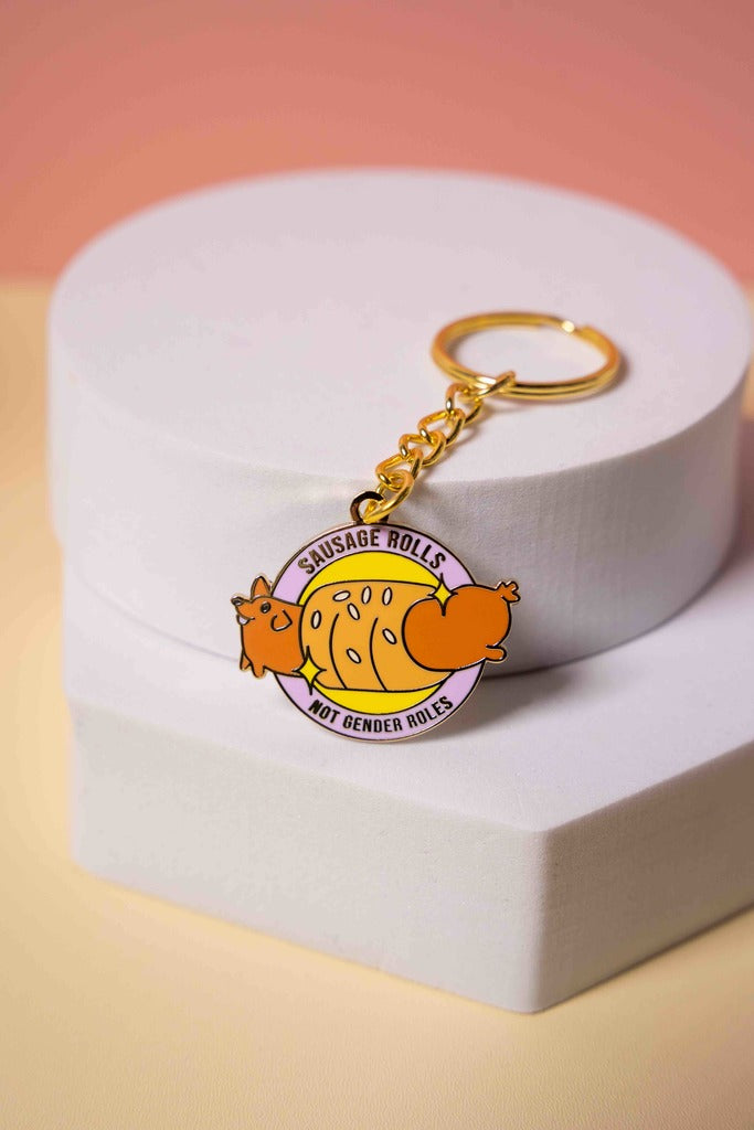 Keychain with a cartoon sausage dog with text 'sausage rolls not gender roles' 