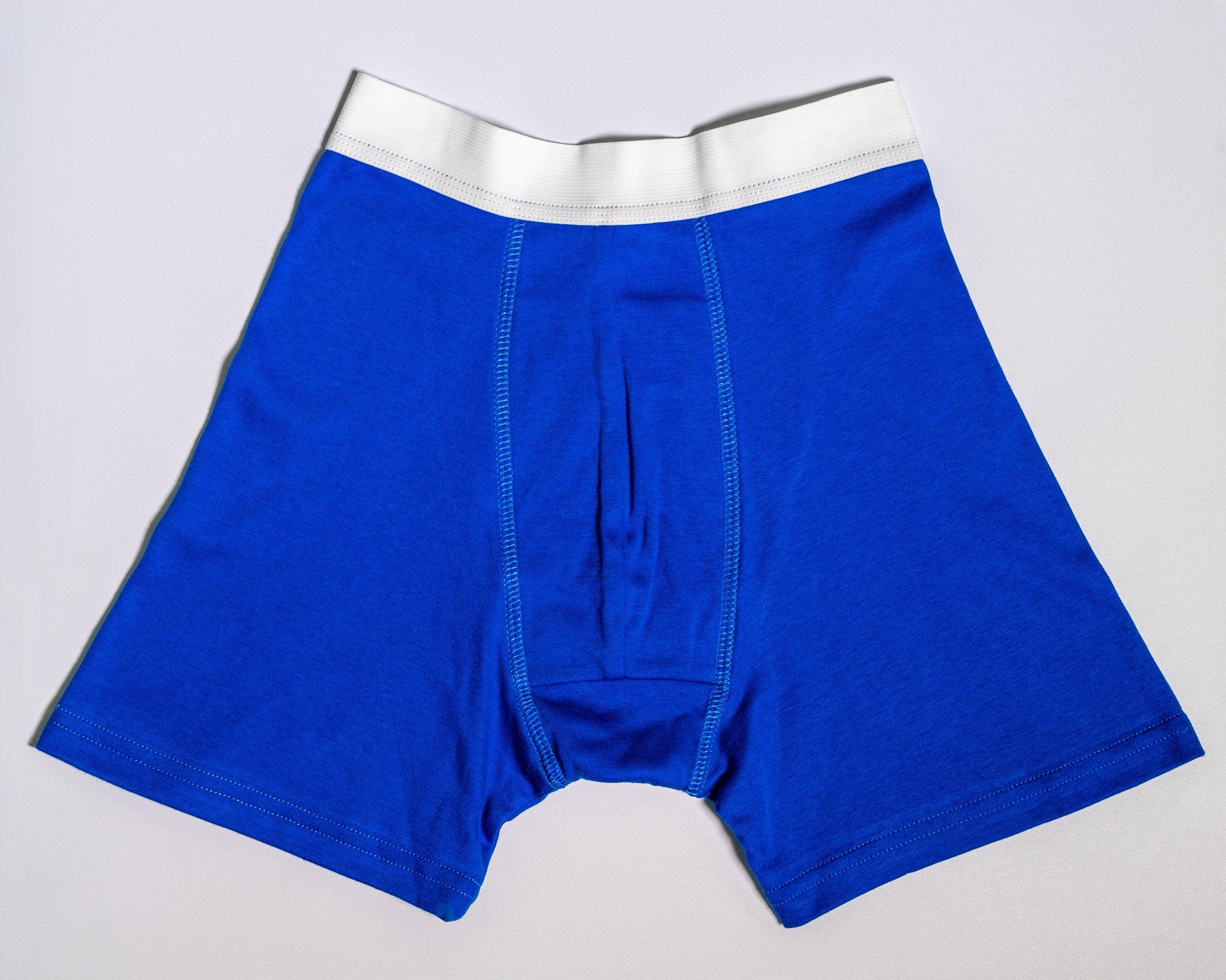Blue boxer briefs with a white waistband on a light gray background