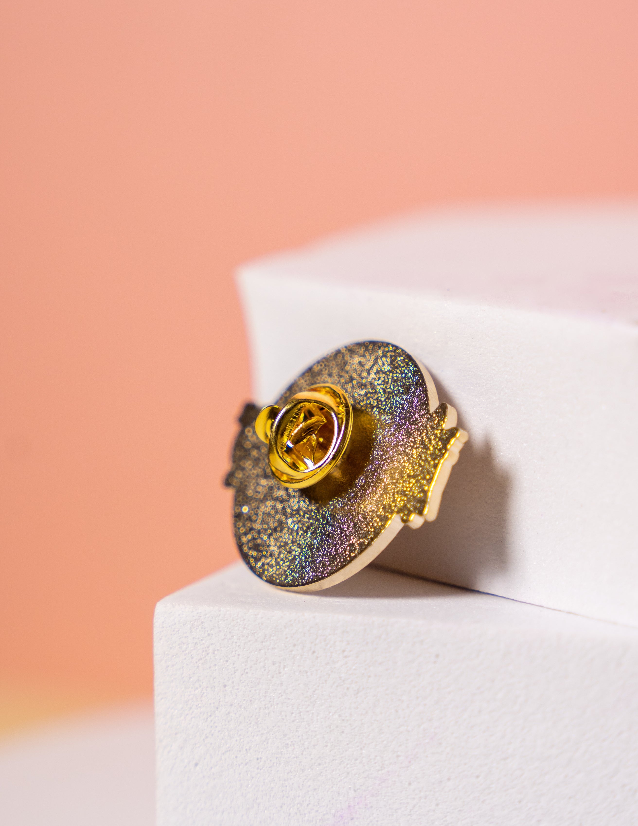 the back of a gold enamel pin showing the metal clutch fixing 