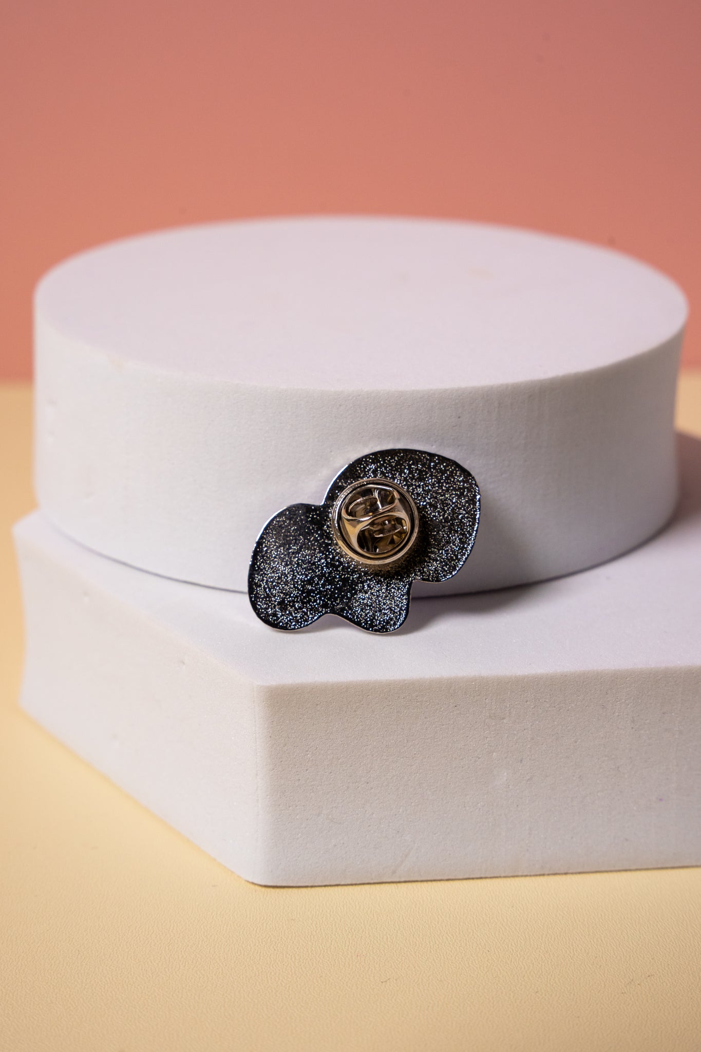 the back of a silver enamel pin showing the metal clutch fixing 