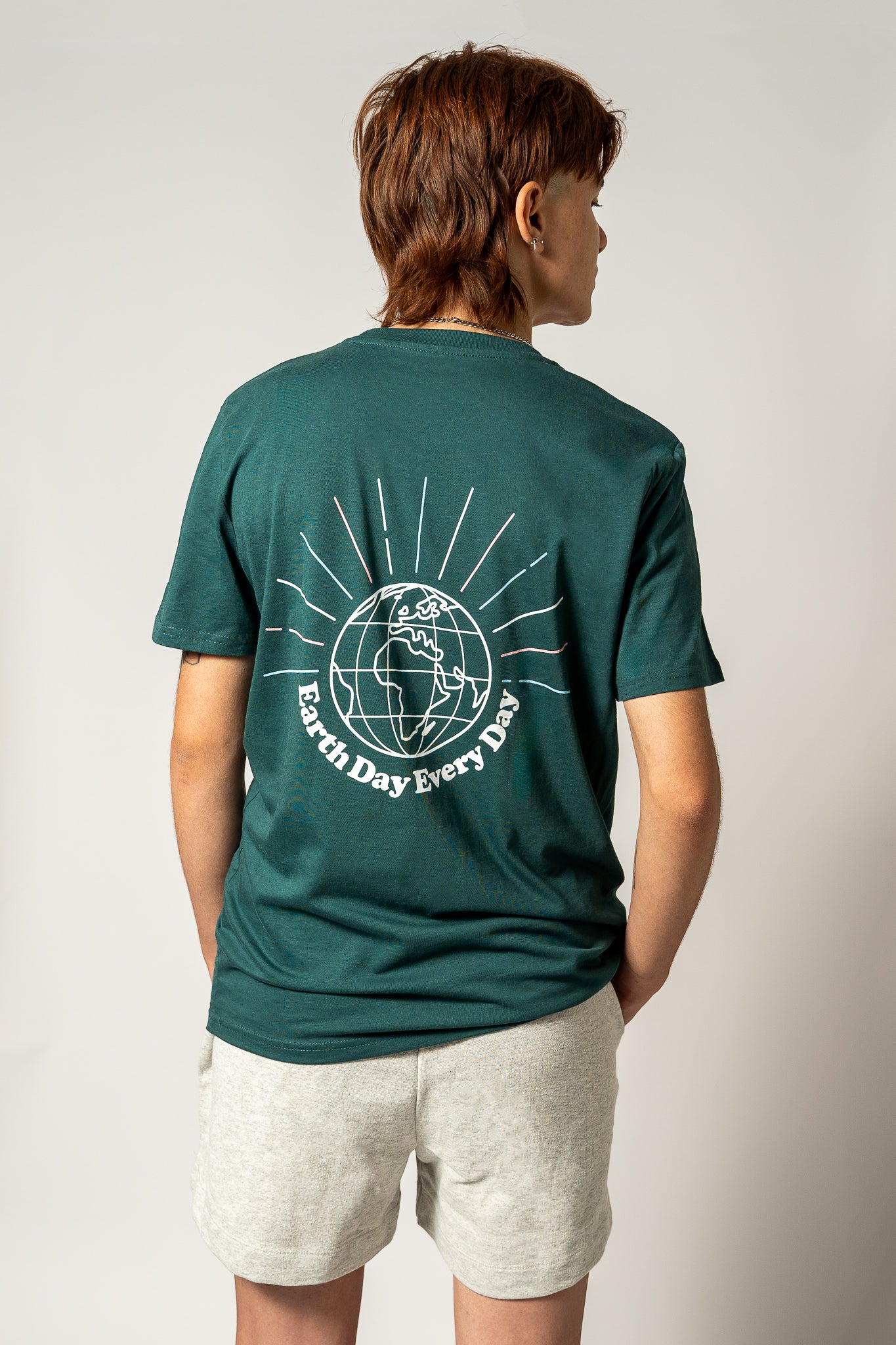 Person wearing a green t-shirt with an "Earth Day Every Day" graphic design on the back, standing against a plain background